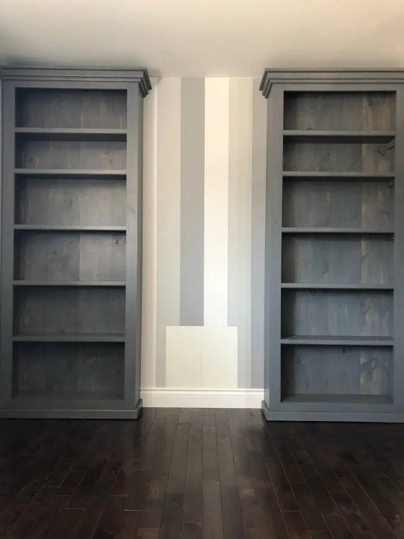 Deux bibliothèques jumelles en pin teint gris bleuté, six cases chacune et corniche moulurée, chez un client