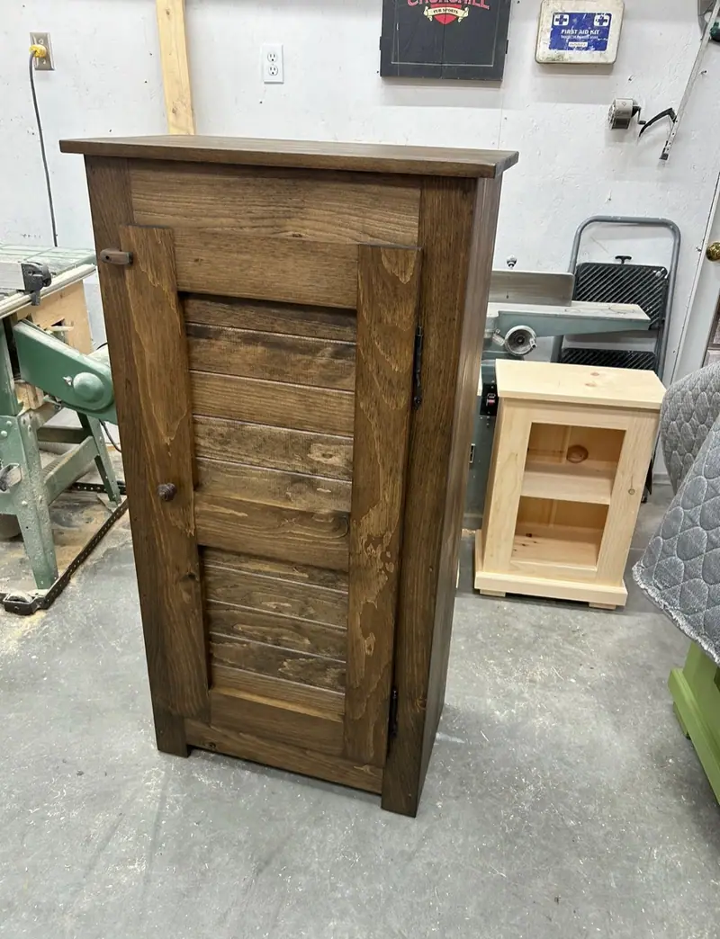 Armoire une porte en pin teint foncé, porte en lambris horizontal.
