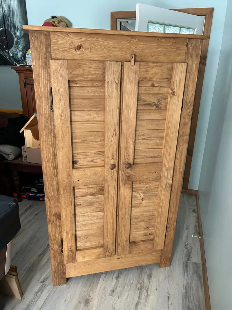 Armoire en pin massif à dessus carré et portes à panneaux de lambris posé à l’horizontale.