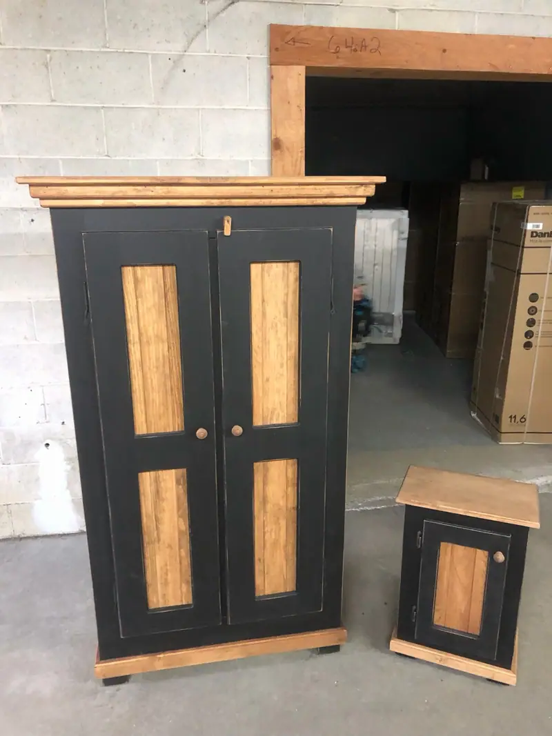 Armoire en pin à portes de lambris peintes noir, moulure de couronnement et plinthe laissées en pin naturel.