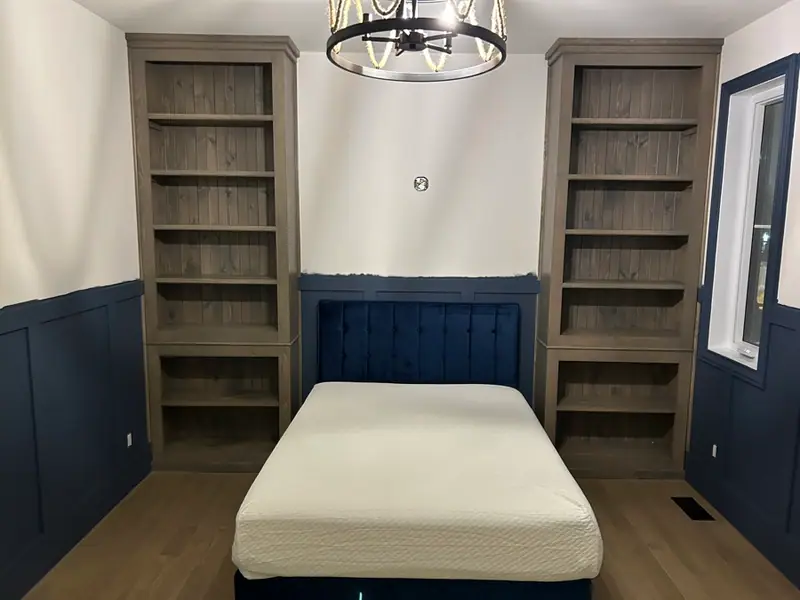 Bibliothèques intégrées sur mesure en pin grisé de chaque côté d’un lit, par un ébéniste des Laurentides