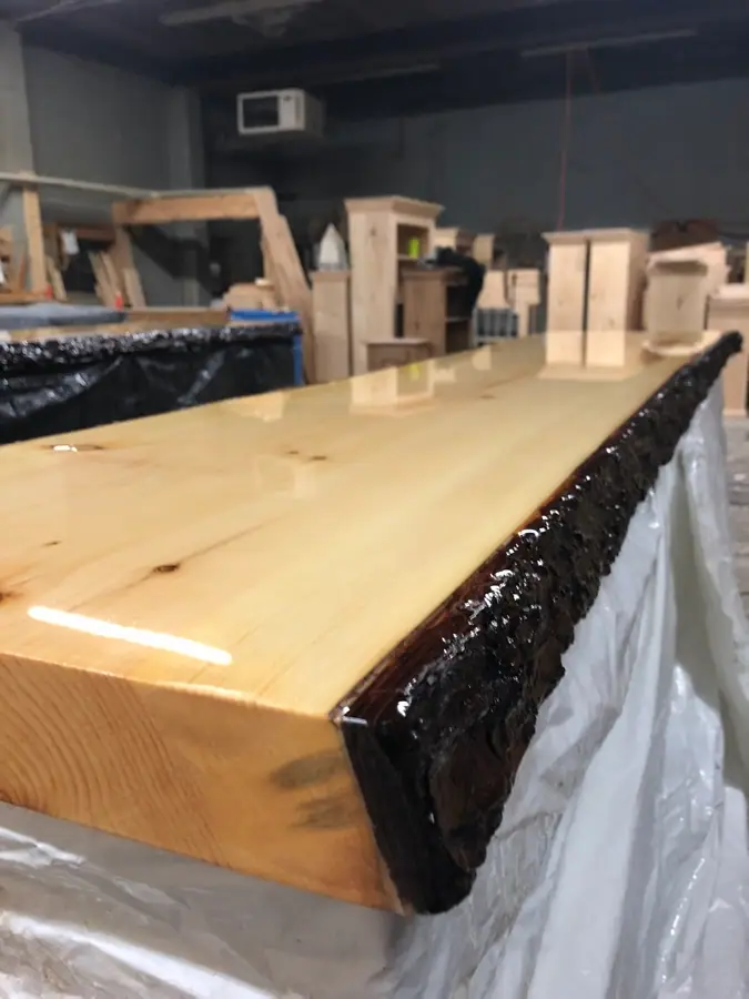 Long comptoir en pin clair à tranche d’arbre, écorce scellée à l’époxy, à l’atelier, par un ébéniste près d’Huberdeau.