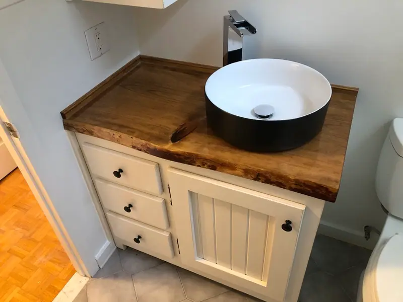 Vanité en pin peinte crème, comptoir en tranche d’arbre au fini époxy et vasque ronde, salle de bain de chalet